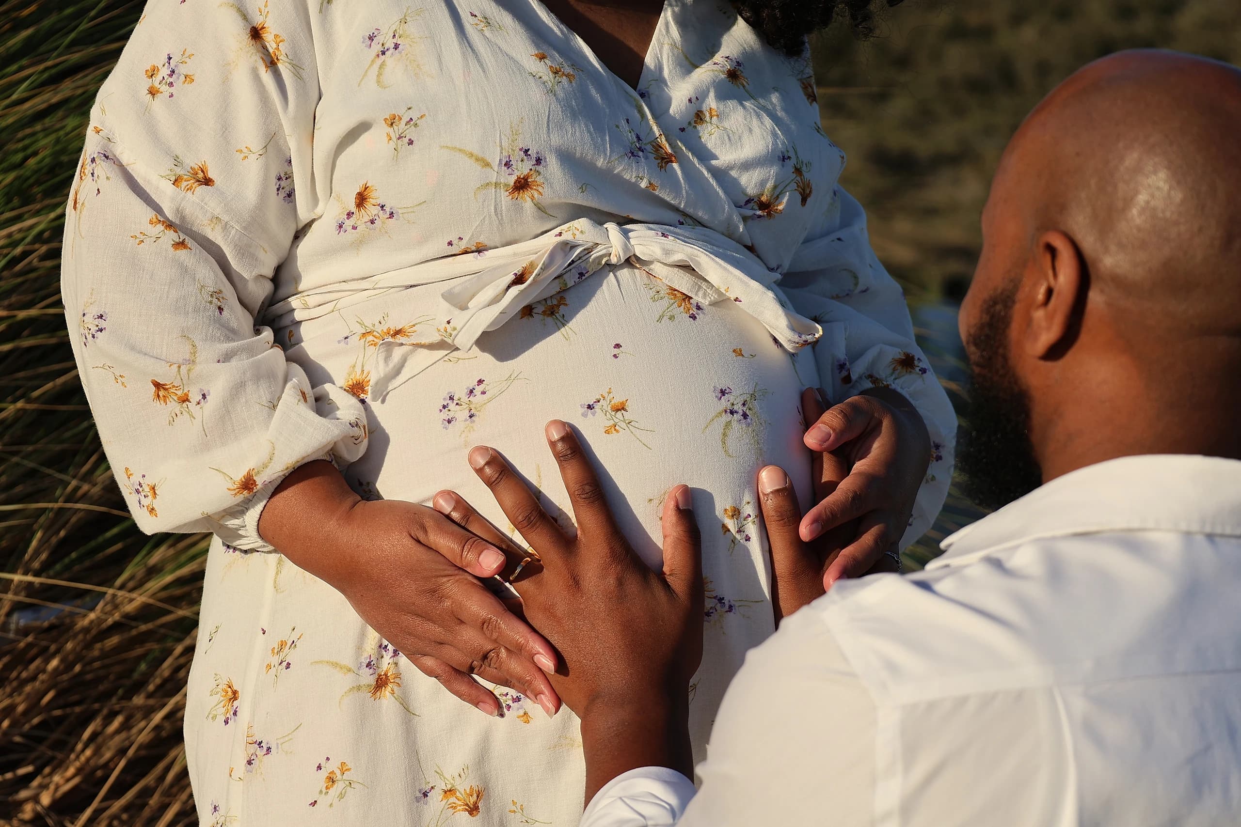 Un couple attend un enfant, les mains posées sur le ventre de la future maman.
