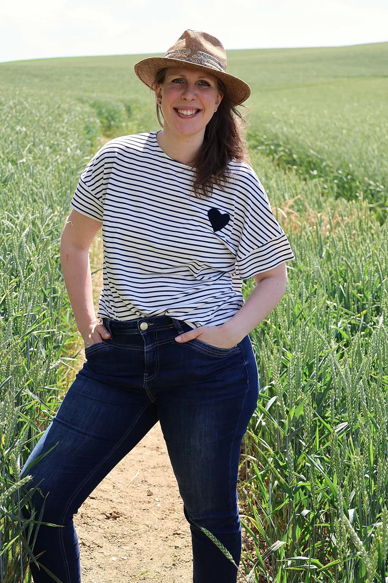 Portrait souriant d'une femme en chapeau dans un champ de blé ensoleillé